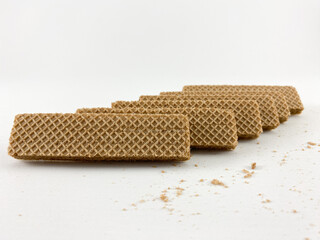 crispy wafer sticks arranged in a staggered pattern on a white background. The wafer sticks have a light brown color and a delicate texture. Wafers with chocolate flavored cream on a white background