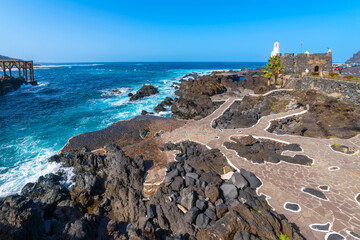 The bell tower and walls of the Castle of San Miguel overlooking the sea and rugged volcanic shoreline at Garachico, on the Canary Island of Tenerife, Spain.