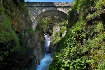 Fototapeta premium Stone bridge and high waterfall around Hotel Pont d'Espagne on trail from Cauterets to lake Lac de Gaube. Pyrenees National Park, France.
