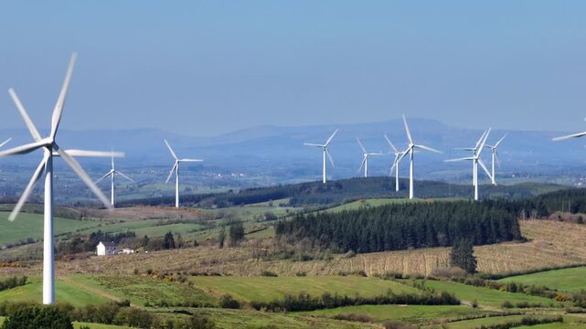 Wind Turbines, Cornasaus, County Cavan, Ireland, April 2023. Drone tracks from left to right with a Telephoto lens as wind turbine blades rotate clockwise with the mountains of Ulster in the distance.