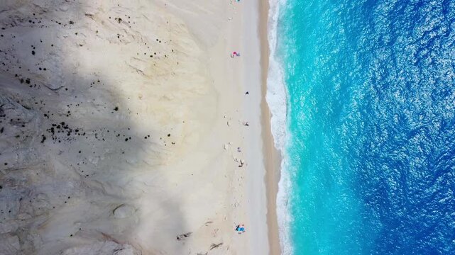 Top-down aerial view of Lefkada beach with turquoise sea water bordered by white mountains