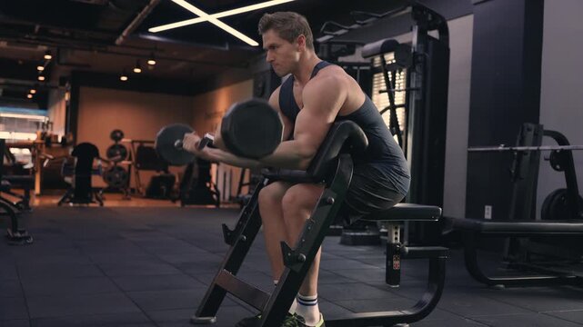 American Fit AthletIc Caucasian Man Doing Barbell Scott Bicep Curls Workout at Modern Gym. Sporty Male Building Biceps Brachii Muscle As Well As The Brachialis with Determination - full body shot