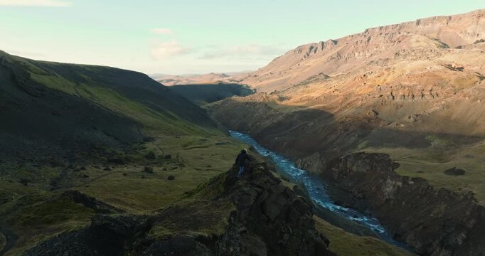 Man Gazes At Haifoss Waterfall From Rocky Outcrop
