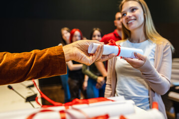 Elderly male teacher awarding diploma to young female student in an amphitheater.
