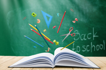 Pencils, ruler, sharpener, shavings and scissors school supplies fly out of open black cover book on background of school green board with sunbeams. Back to school training concept. Empty background.