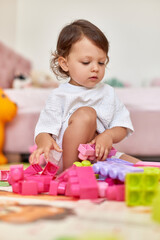 cute baby girl playing with colorful toys bricks at home