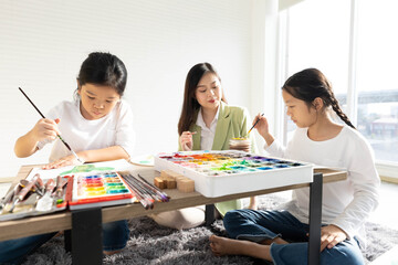 Children and Teacher drawing and filled with colorful paints in the classroom