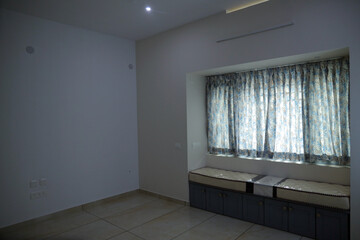 An empty room with storage bench near to the window