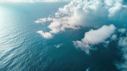 Top view of the ocean with a veil of fluffy clouds. A tranquil and dreamy scene from above, with the sea and sky intertwined.