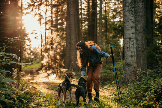 A smiling woman with a small dog hiking in the forest