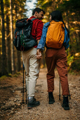 Happy couple holding hands while hiking together in mountains with backpacks