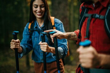 Mid adult couple using poles while exploring nature.
