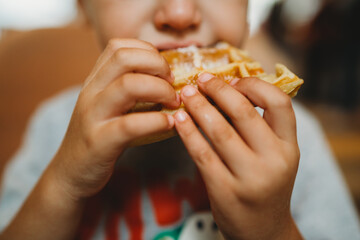 Close up of young child hands holding eating waffle