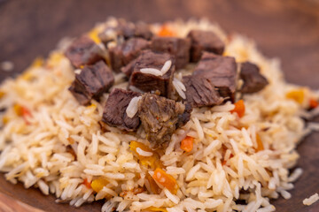 A plate of rice and meat with carrots on top