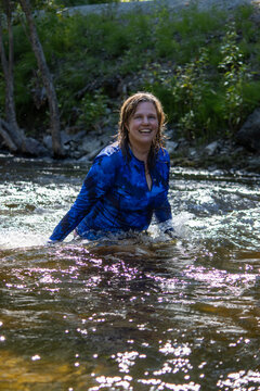 Woman happily playing and splashing in a creek, enjoying the outdoors