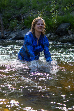 Woman happily playing and splashing in a creek