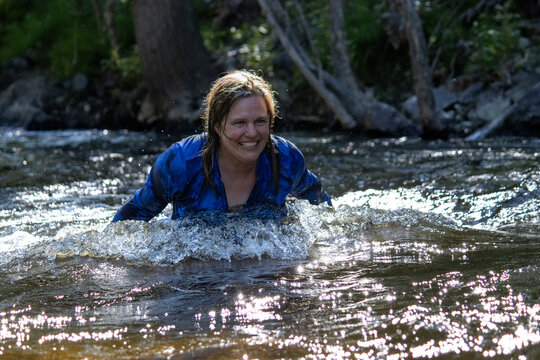 Woman joyfully splashing and playing in a creek enjoying nature