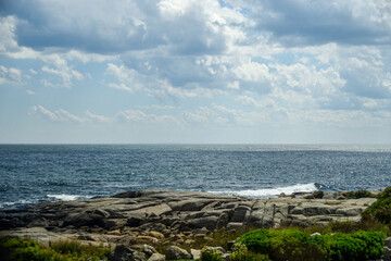 Scenic ocean view with rocky coastline under a cloudy sky.