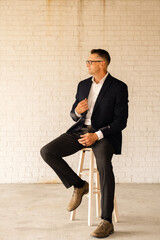 business man sitting on stool looking to the side