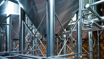 Complex network of gleaming stainless steel pipes at brewery, intricate infrastructure essential for modern beer production.