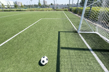 Soccer ball on artificial bright and dark green grass at public outdoor football stadium
