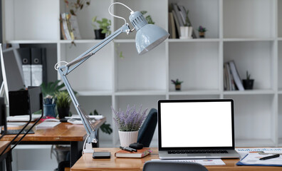 Laptop computer mockup white screen and accessories on a white desk in a modern office. Office workspace