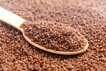 Organic gluten free buckwheat couscous grains in bamboo spoon.