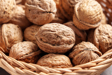Fresh walnuts seeds in authentic wooden braided rattan bowl. Organic whole uncracked nuts