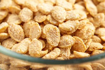 Crispy breakfast cereal flakes in the form of grains in a glass transparent kitchen bowl