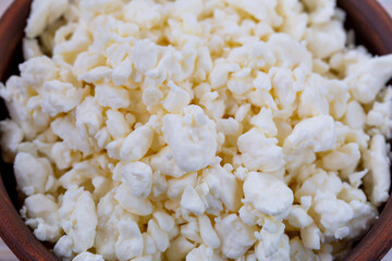 Fresh cottage cheese in a brown earthen bowl close-up