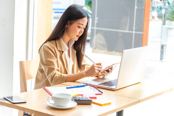 Women Freelance work on computer pointing with color pen electronic gadgets dropped around on table