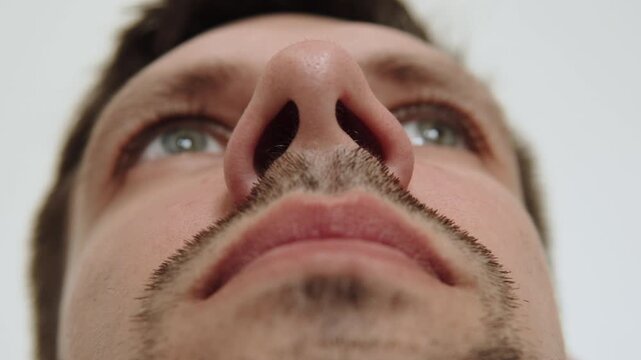 Caucasian man breathes and widens nostrils of his nose closeup. Intense emotional state and inhaling more oxygen. Psychological portrait of person with problems.