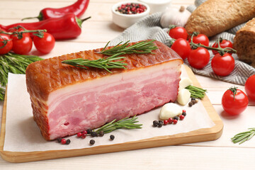Piece of raw bacon with spices and cherry tomatoes on white wooden table