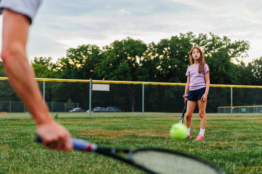 A girl playing tennis with father in field