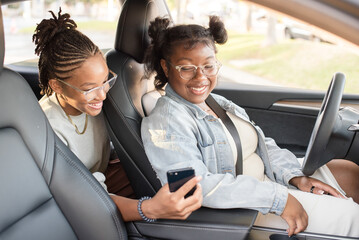 Young women looking at a phone in a car