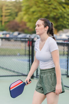 Young woman focused during a pickleball game on outdoor court.