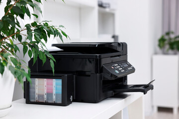 Modern printer with paper on table in office