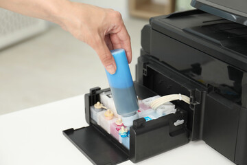 Woman refilling ink in modern printer at workplace indoors, closeup