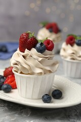 Tasty cupcake with different berries on light grey table, closeup