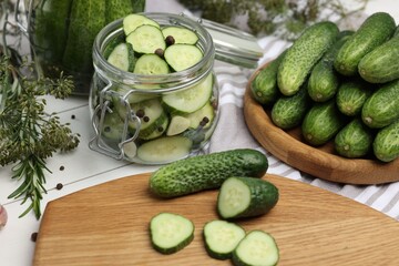 Homemade pickles. Fresh cut and whole cucumbers on white wooden table, closeup