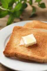 Delicious toasted bread slices with butter on table, closeup