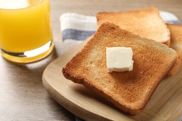 Delicious toasted bread slices with butter served on wooden table, closeup