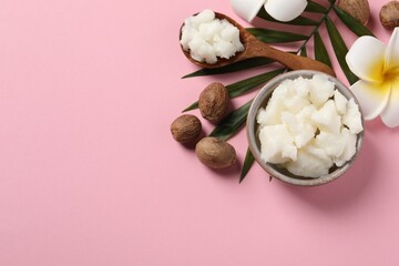 Shea butter in bowl, flower and nuts on pink background, flat lay. Space for text