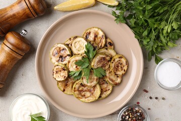 Tasty grilled courgette slices served on grey textured table, flat lay