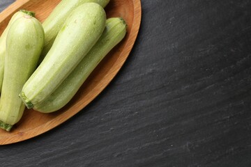 Fresh zucchinis on dark textured table, top view. Space for text
