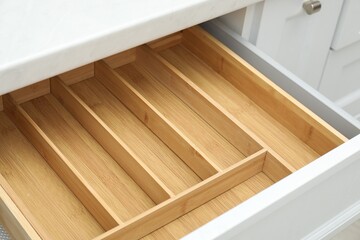 Open drawer of kitchen cabinet with space for cutlery, closeup