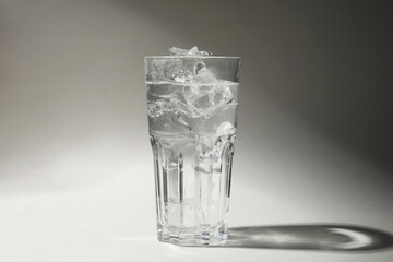 Refreshing water with ice in glass on grey background