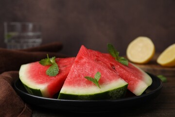 Fresh watermelon slices with mint leaves on wooden table, closeup
