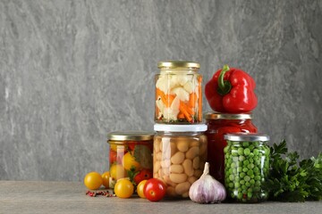 Different pickled products in jars on wooden table