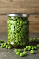 Tasty pickled green peas in jar on grey textured table, closeup